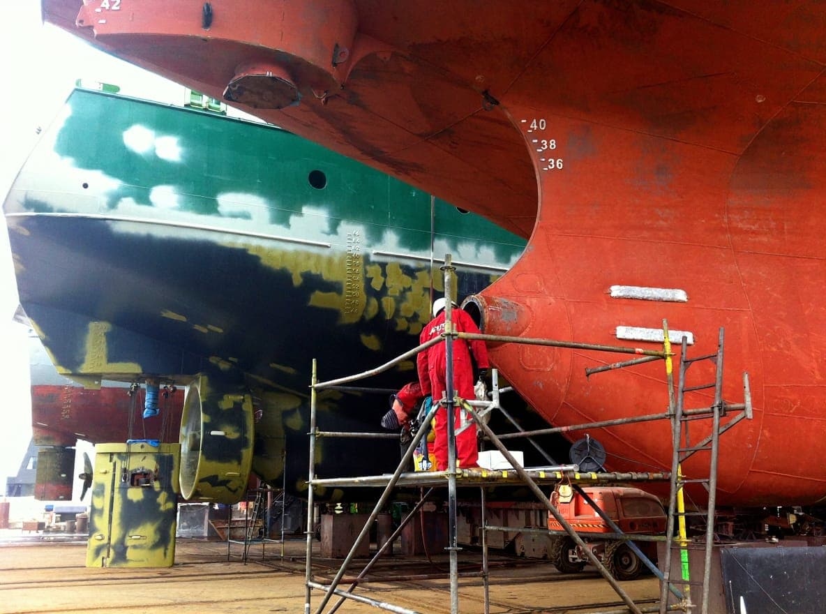 OSM technician on scaffolding under ship hull performing line boring